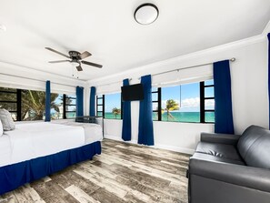 A bedroom with a bed, a ceiling fan, a TV, and a view of the ocean. - Hollywood Beach Hotels (Hollywood)