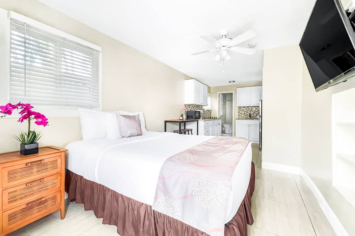 A bedroom with a bed, bedside table, and a potted orchid.