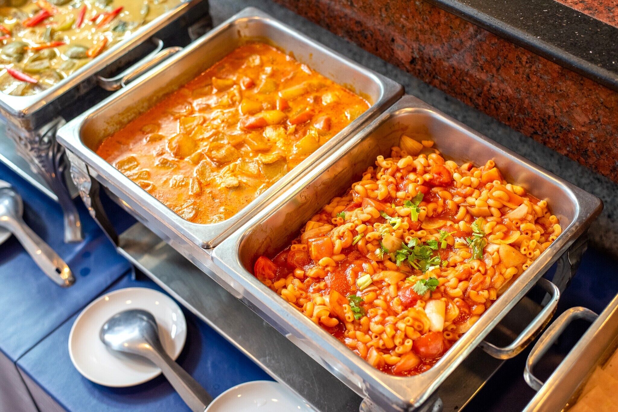 A buffet with various dishes including pasta and a creamy soup.