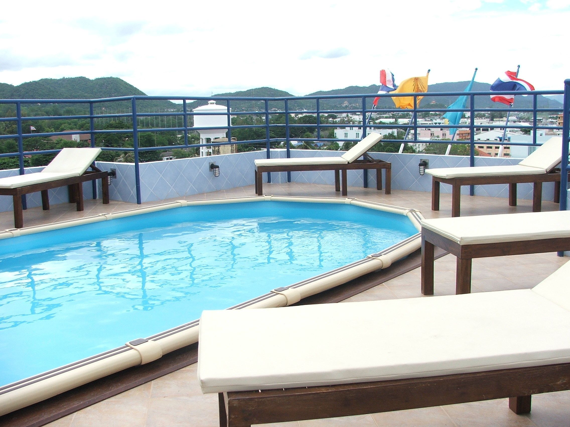 A rooftop pool with lounge chairs and a view of the cityscape and hills in the background.