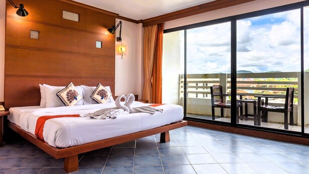 Un dormitorio amplio con una cama grande, cabecera de madera y un balcón con mobiliario exterior.