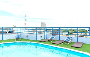 Una piscina al aire libre, sillones reclinables de piscina