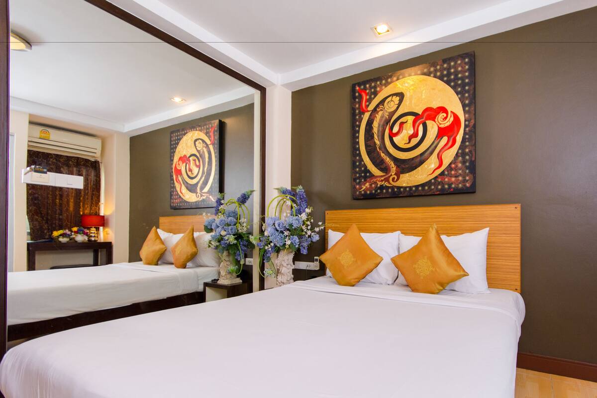 A hotel room with two beds, a large mirror, and artwork on the walls.