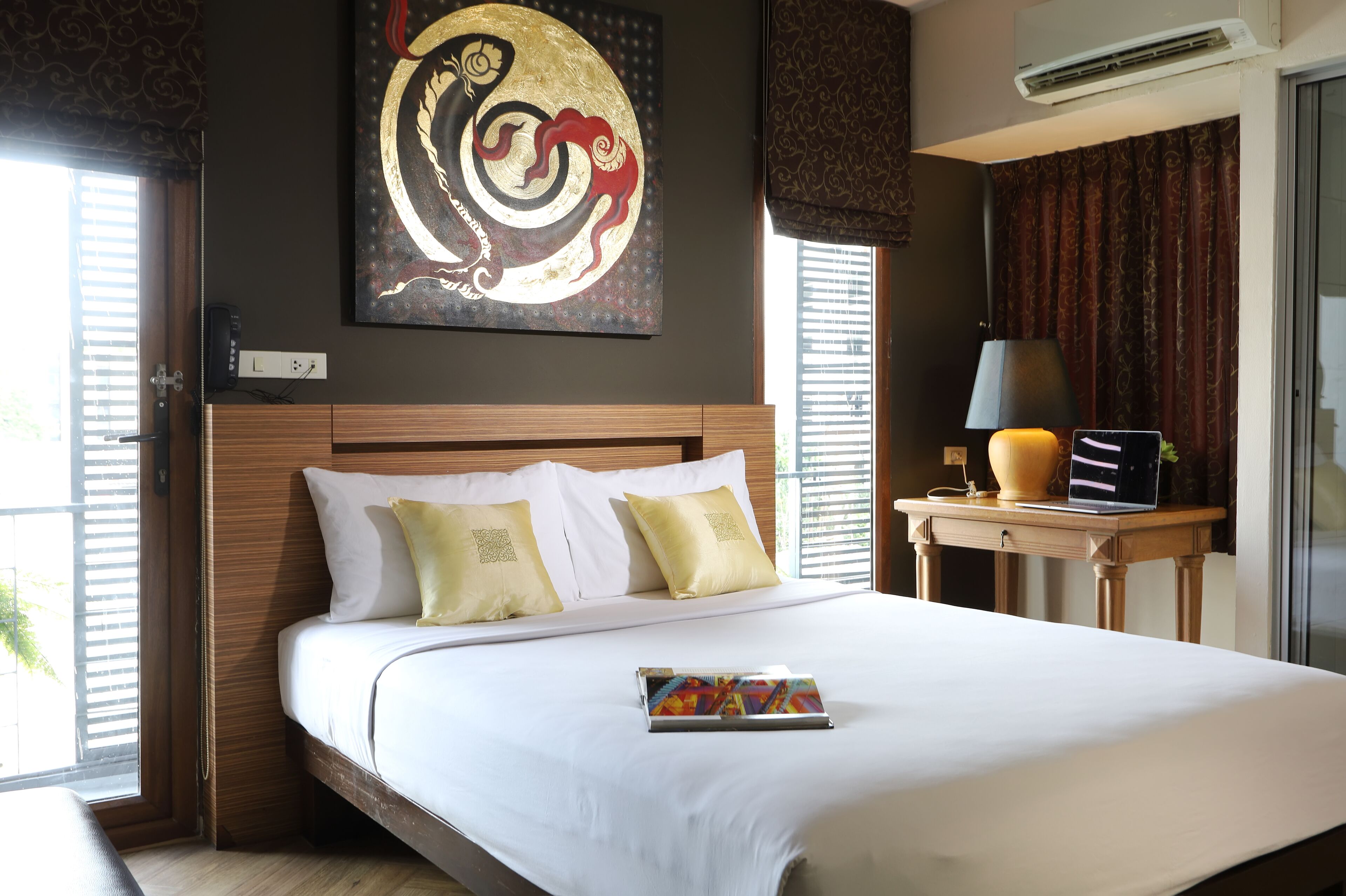 Ein Hotelzimmer mit einem großen Bett, einem Nachttisch mit Lampe und einer Wandklimaanlage.