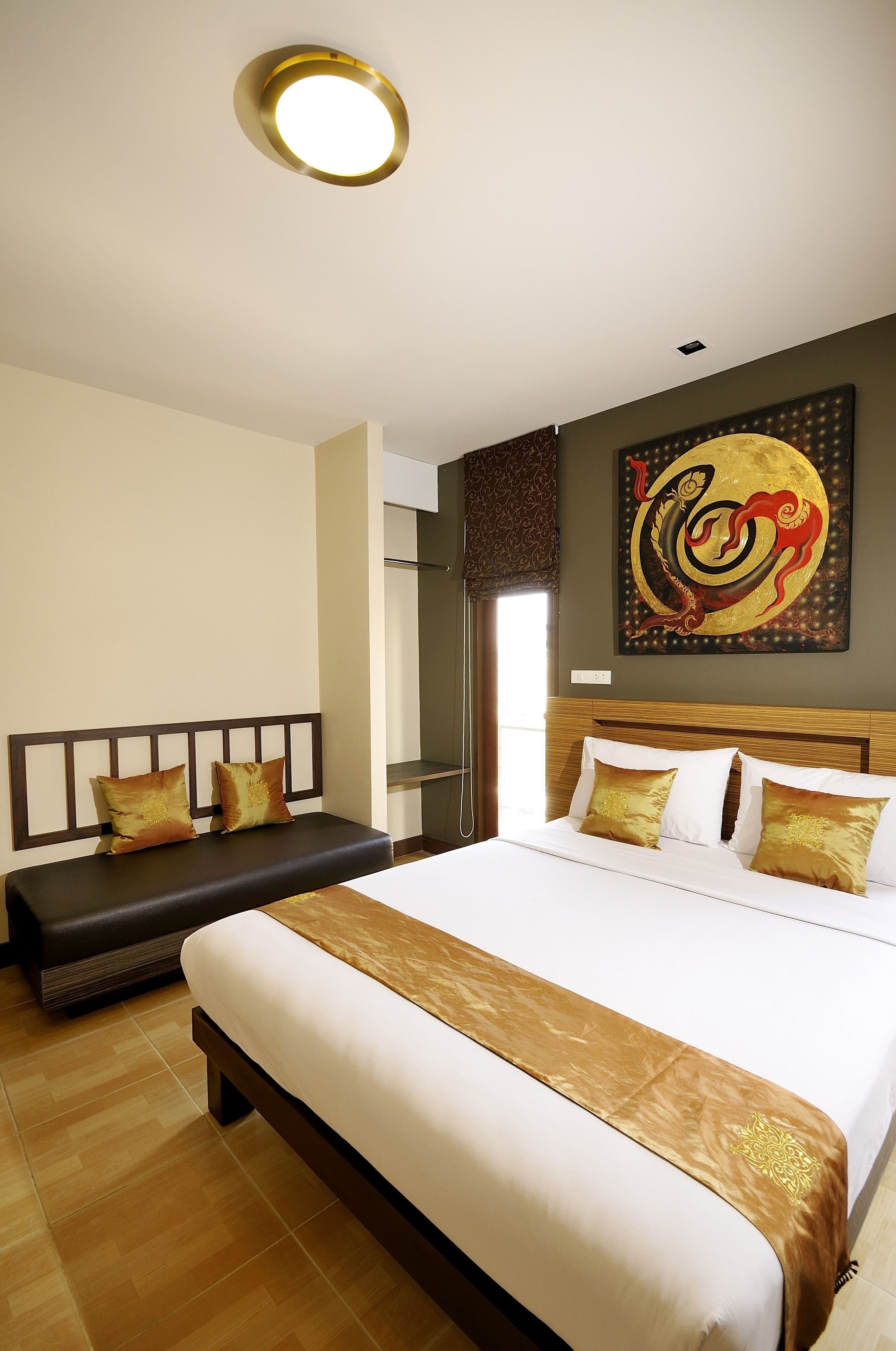 Habitación de hotel con una cama grande, un banco y una obra de arte colgada en la pared.