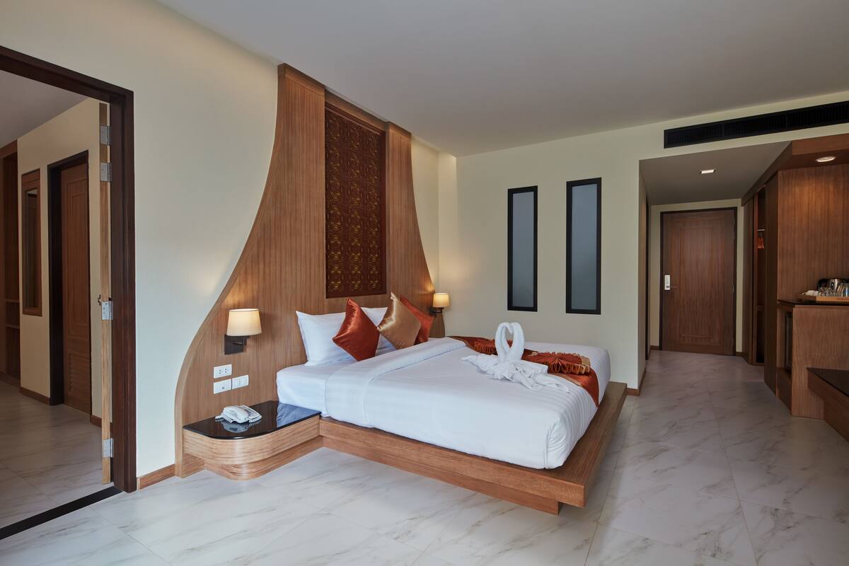 A modern hotel room with a bed, bedside table, lamp, and a mirror.