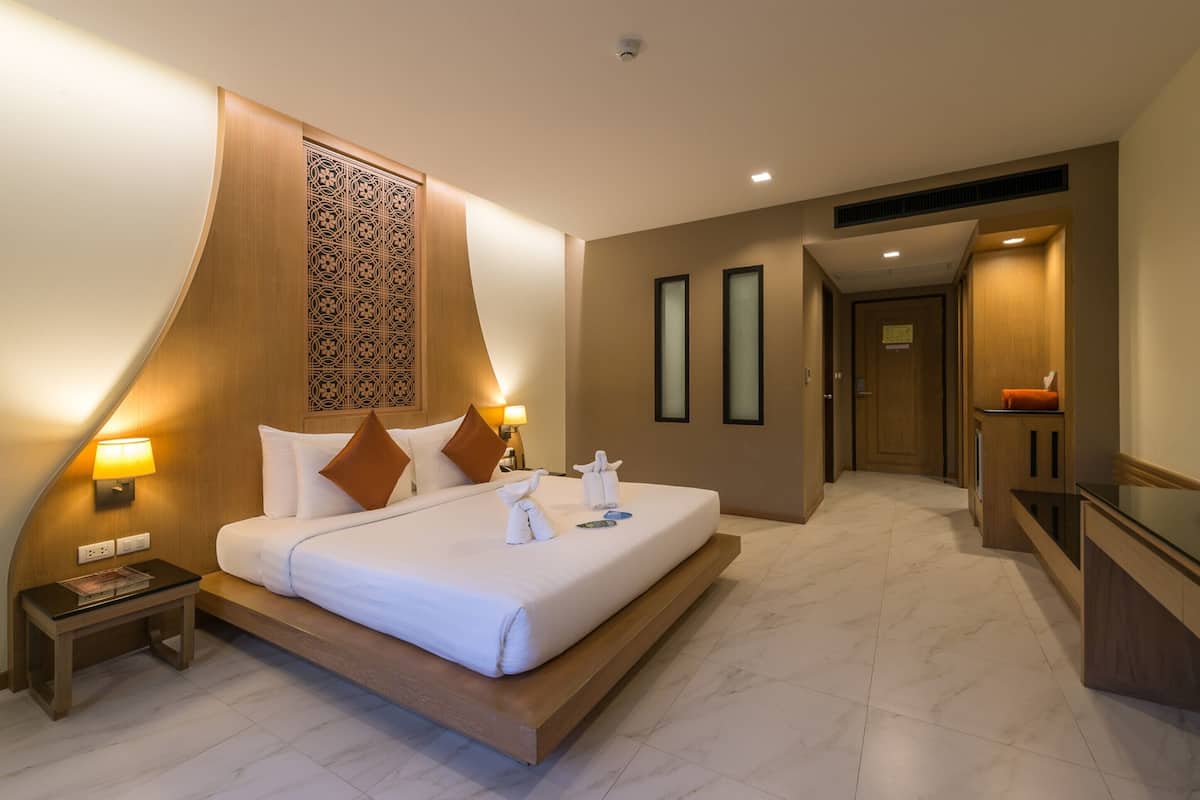 A modern hotel room with a large bed, bedside lamps, a wooden headboard, and a small table with a magazine.