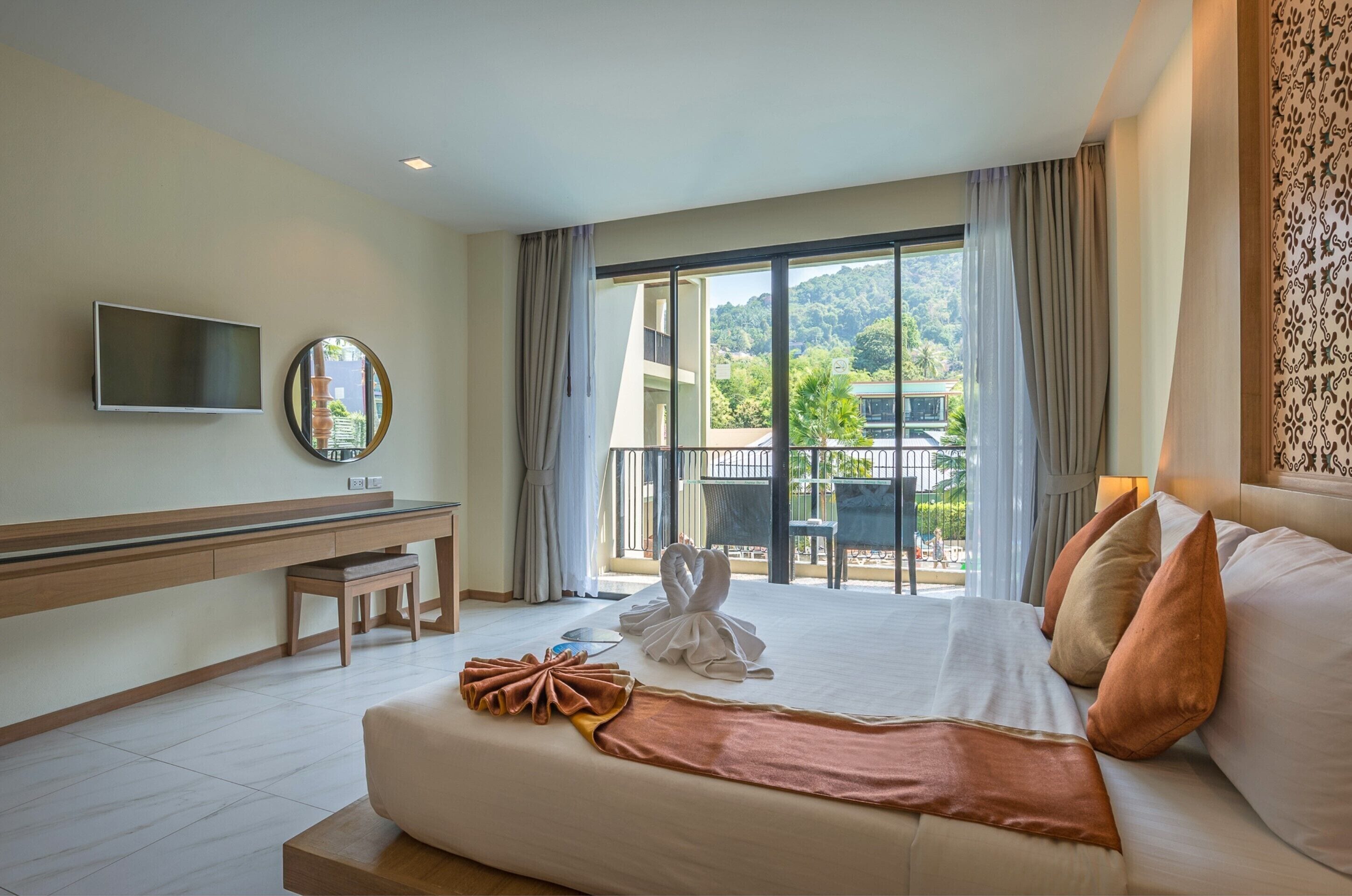 A hotel room with a large bed, a desk, a flat-screen TV, and a view of the outdoors.