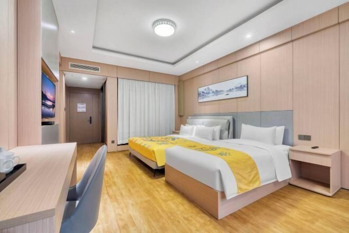 A hotel room with a bed, bedside table, and a desk with a chair.