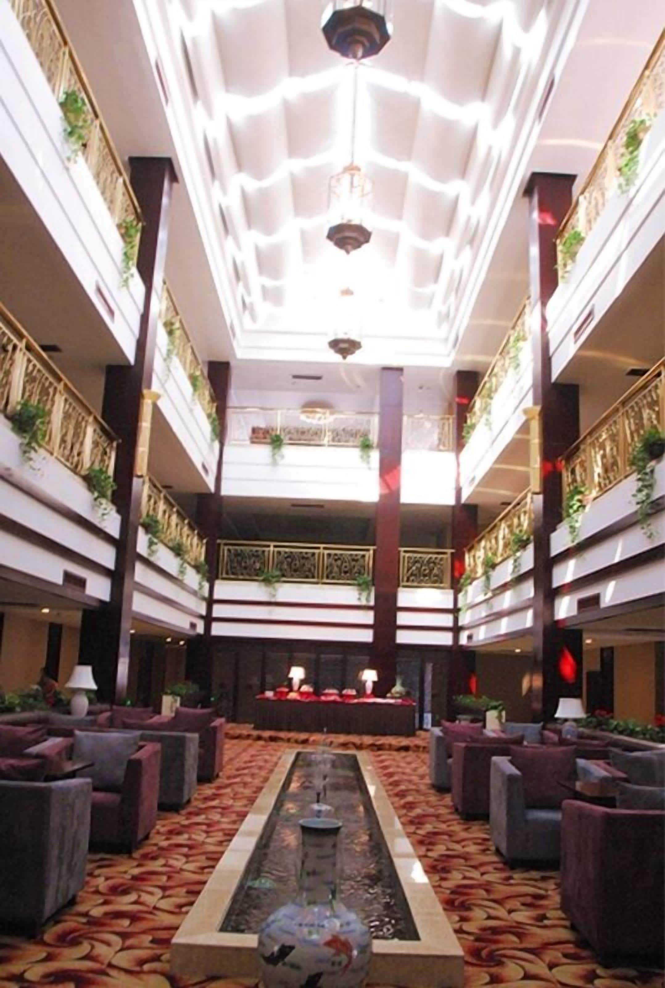A hotel lobby with a central water feature, multiple levels with balconies, and seating areas.