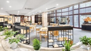 Een ruime binnenruimte met diverse zithoekjes, waaronder tafels en stoelen, en een centraal decoratief element.