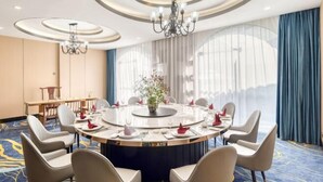 Een vergaderruimte met een ronde tafel, stoelen en een kroonluchter.