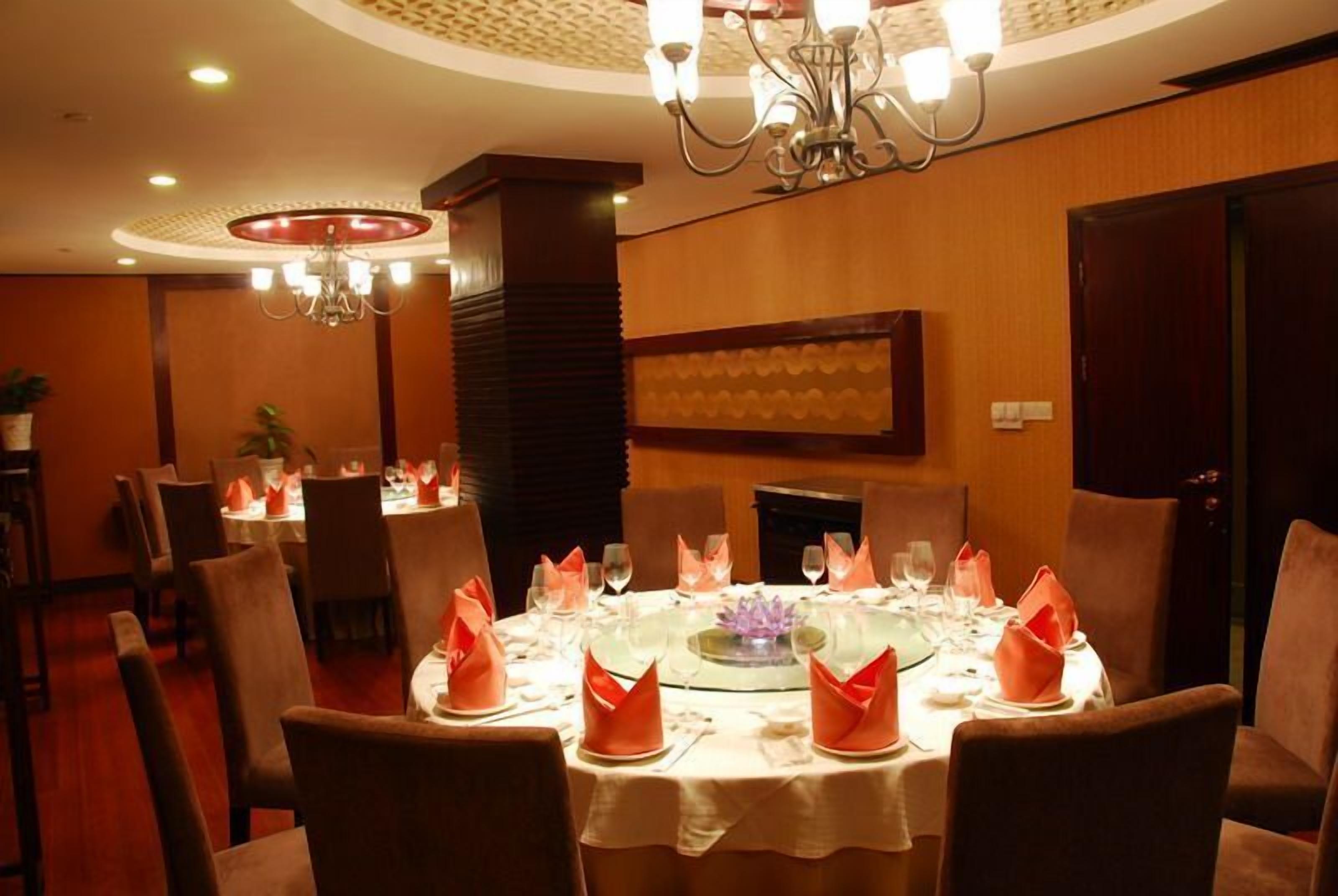 A dining area with round tables set for four, each with a white tablecloth, red napkins, and a purple centerpiece.