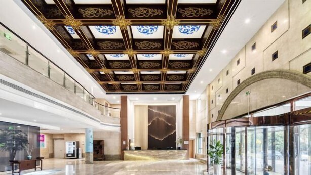 Een ruime lobby met een hoge plafond, een receptiebalie en een glazen gevel met uitzicht op buiten.