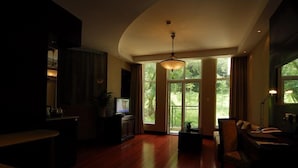 Un salón amplio con suelo de madera, televisor y un ventanal con vistas a zonas verdes.