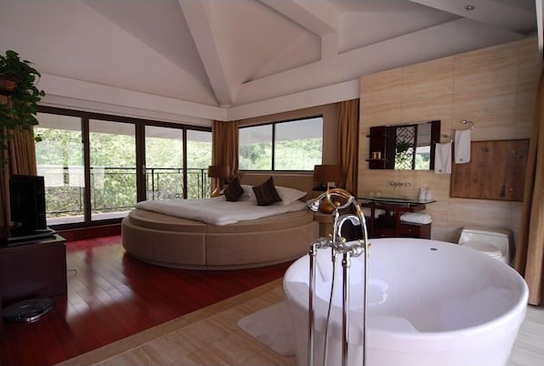 A modern hotel room with a large bed, a separate seating area, a bathtub, and a balcony with a view of greenery. - West Lake Hillview International Hotel (Hangzhou)