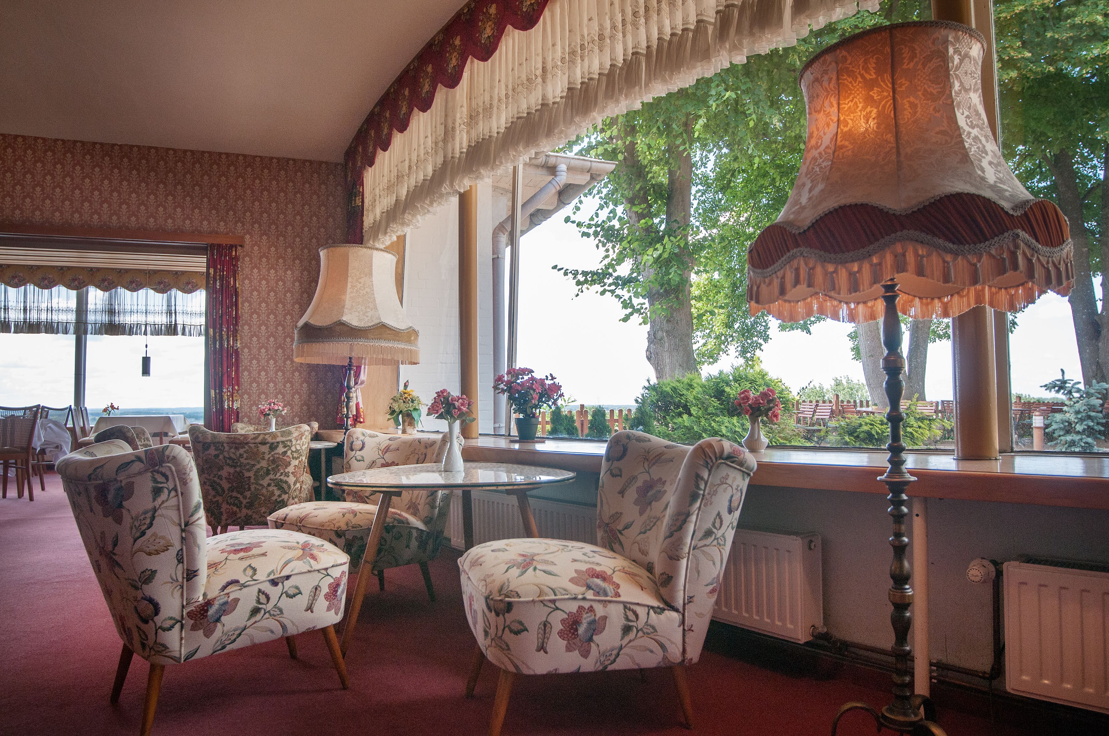 A room with floral-patterned chairs, a table, and a lamp.