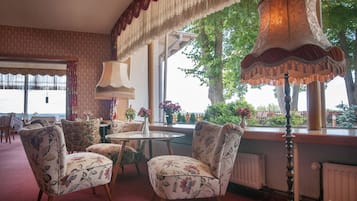 A room with floral-patterned chairs, a table, and a lamp.