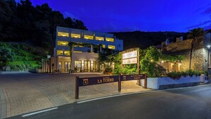 A hotel entrance with a sign reading "Hotel La Torre" and a decorative sign with "Donna Teresa" and "Capopalinuro" on it.