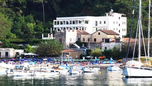 A marina with multiple boats docked, surrounded by buildings and lush greenery.