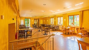 A spacious dining area with multiple tables and chairs, a staircase, and large windows allowing natural light. - Gasthaus Goldener Hirsch (Suhl)