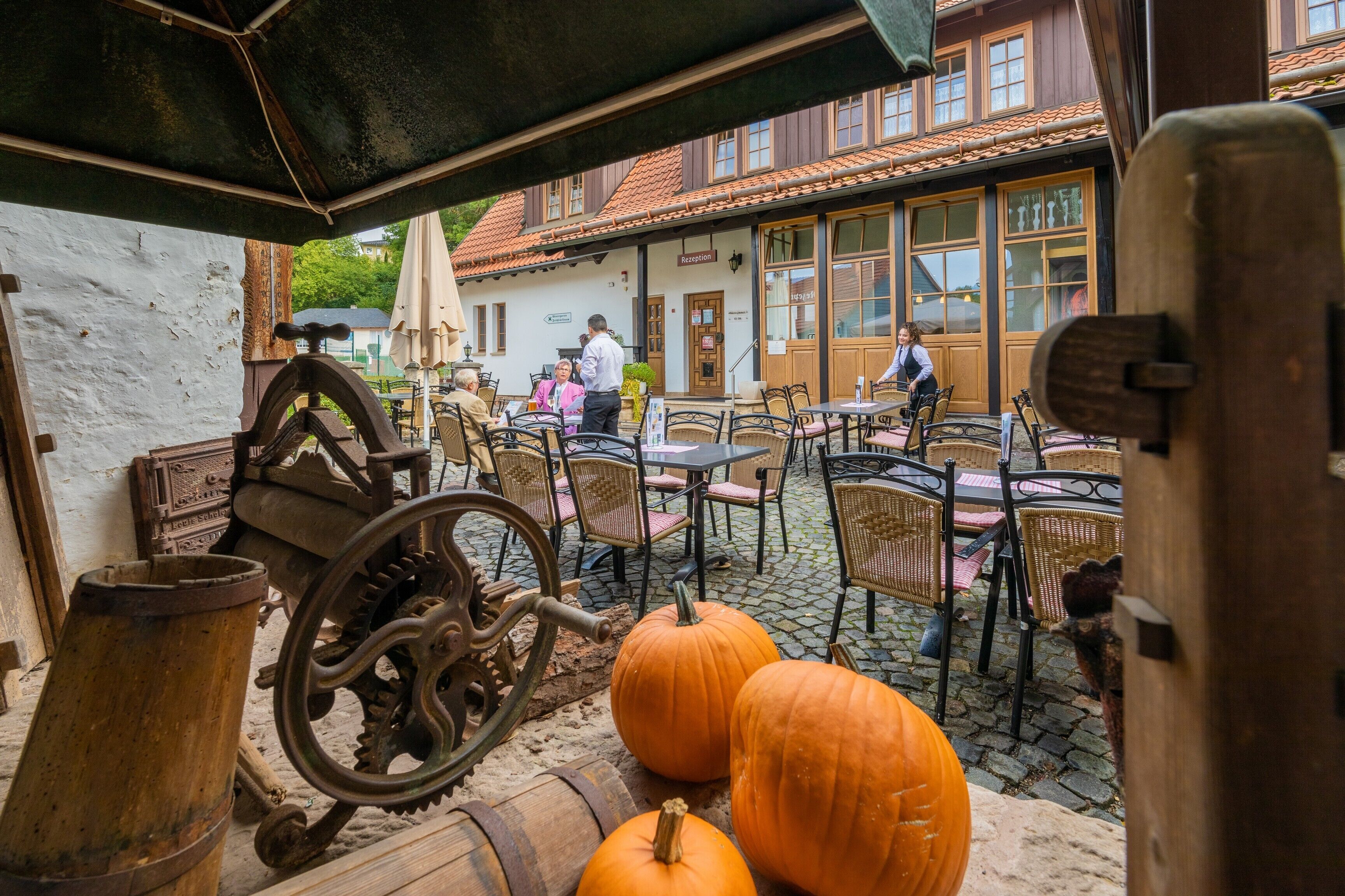 Ein Außenbereich mit rustikaler Möbel, einem großen Holzfass und einem alten Zahnrad.