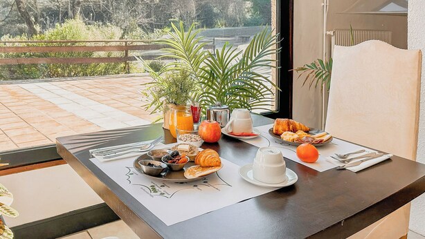 A dining table with breakfast items, a plant, and a view of the outdoors. - Garden & City Capvern-les-Bains (Capvern)