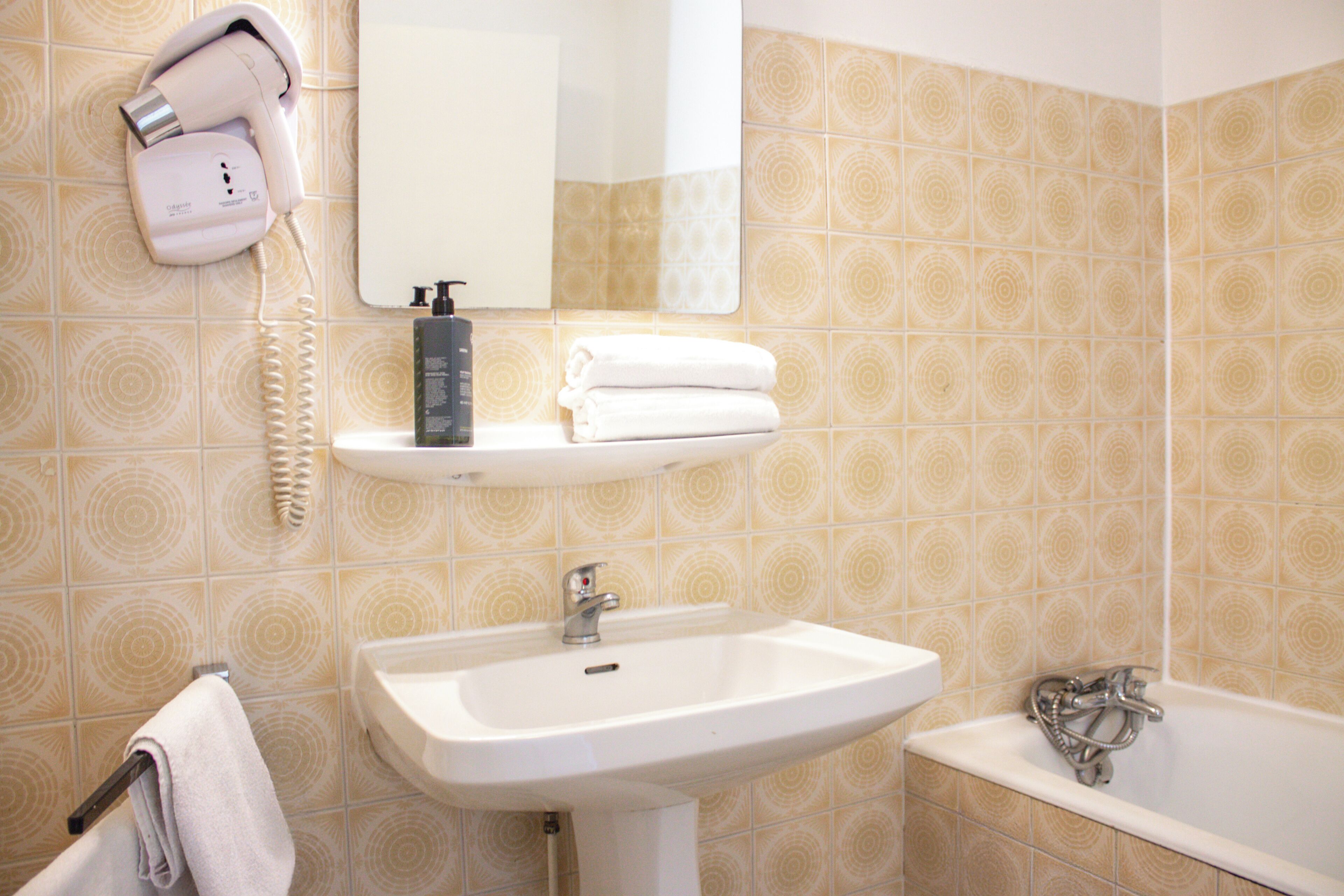 A bathroom with a sink, a mirror, a hairdryer, and a towel rack.