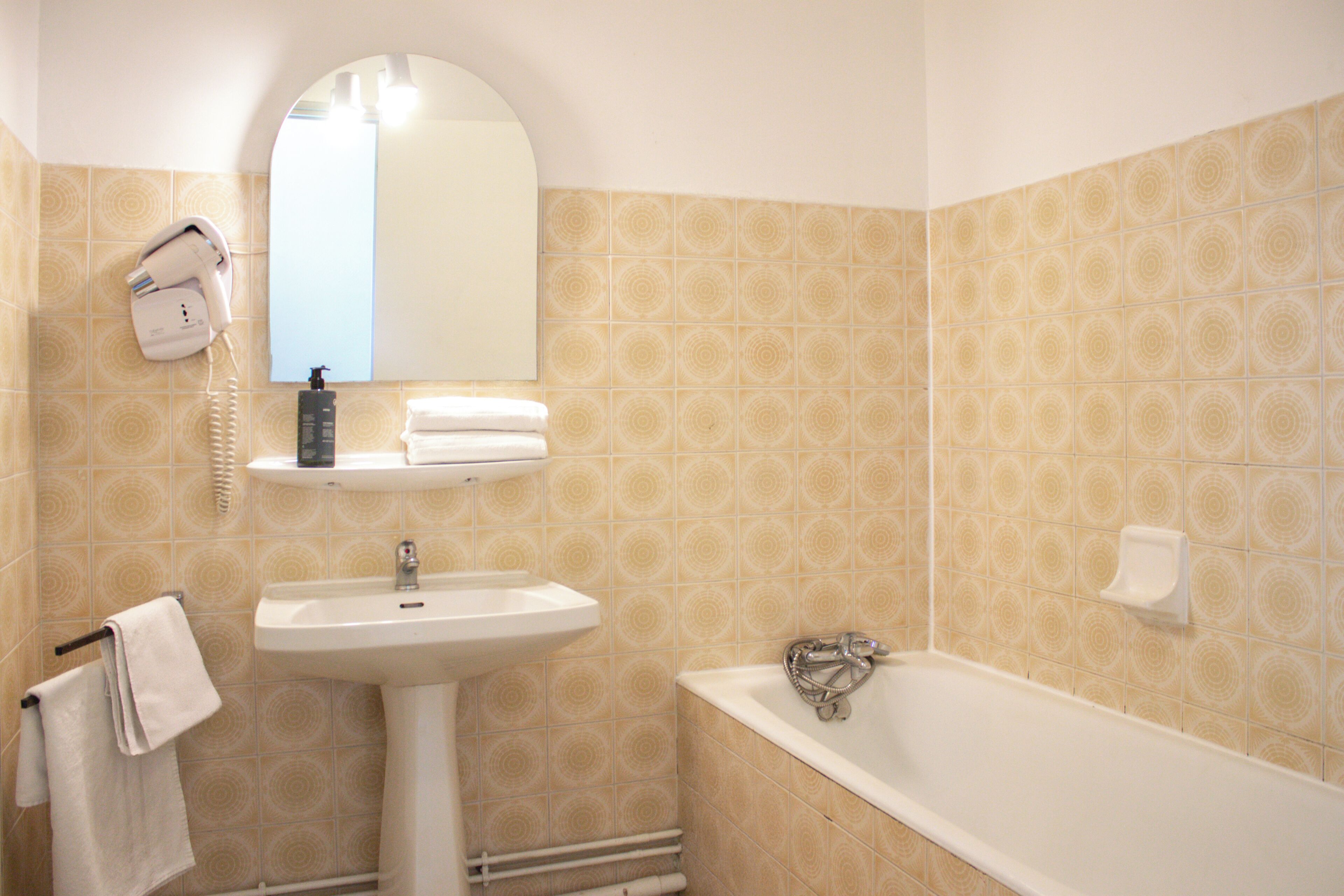 Un baño con lavabo, espejo, secador de pelo y bañera.