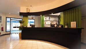 A reception desk with a curved design, a clock, and a sign indicating coffee and breakfast service. - Garden & City Capvern-les-Bains (Capvern)