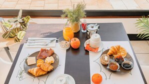 A breakfast setup with croissants, cheese, ham, and fruits on a table with a placemat. - Garden & City Capvern-les-Bains (Capvern)