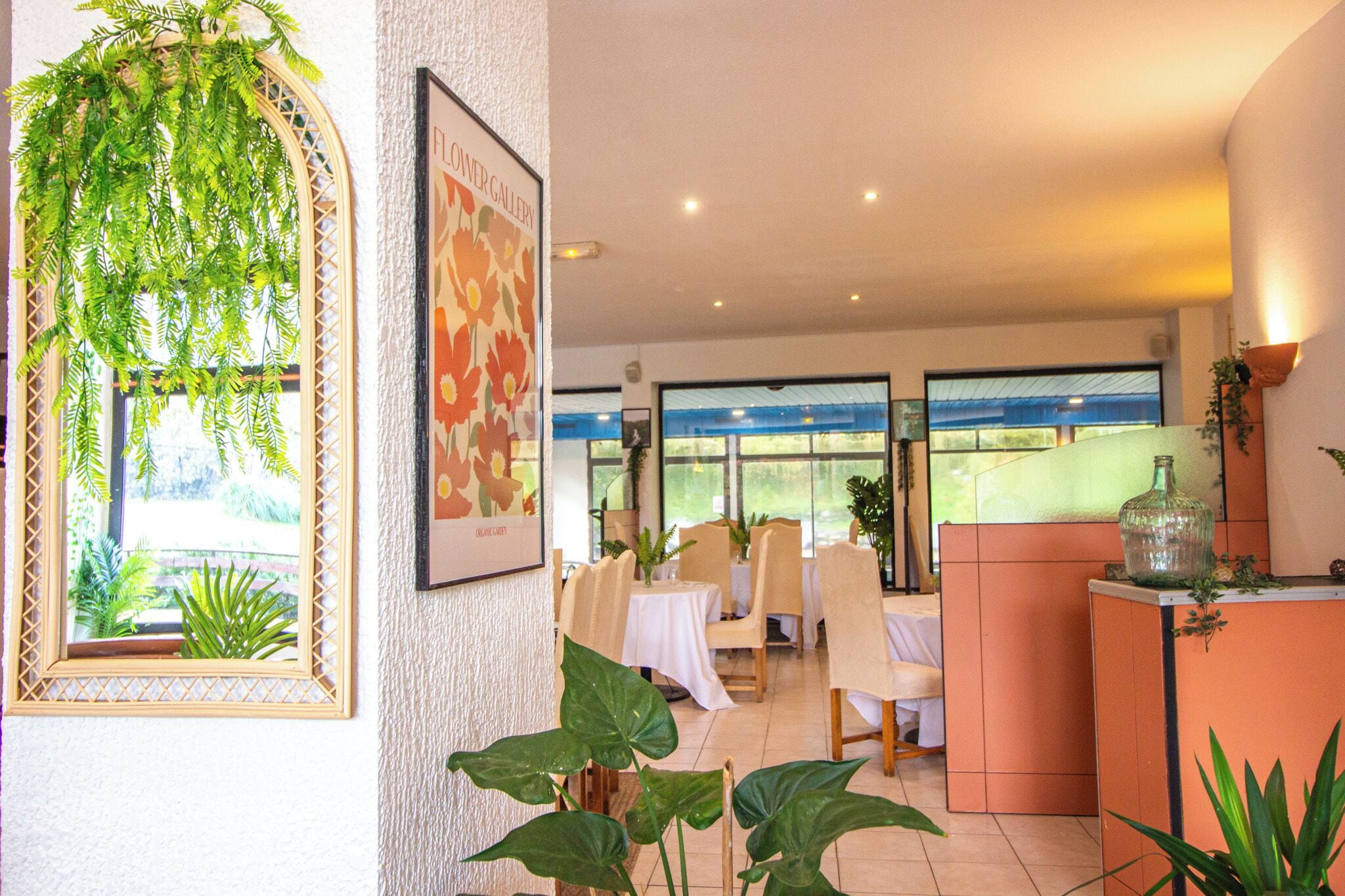 Un interno di ristorante con tavoli, sedie e vista attraverso ampie finestre.
