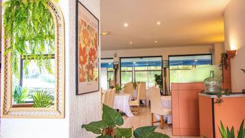 Un interno di ristorante con tavoli, sedie e vista attraverso ampie finestre.