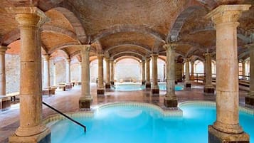 Una amplia piscina interior con techo de ladrillo y columnas.