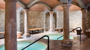 An indoor swimming pool with stone columns and a tiled floor. - Termas De San Joaquin (Ramos Arizpe)