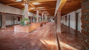 A spacious corridor with brick pillars, tiled flooring, and potted plants. - Termas De San Joaquin (Ramos Arizpe)