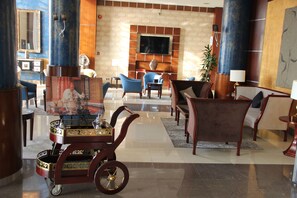 A lobby with a fireplace, seating area, and a television mounted on the wall. - Golden Tulip Al Khobar (Al Khobar)