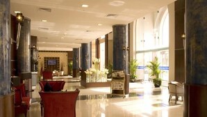 A spacious lobby with high ceilings, marble columns, and a central seating area with red sofas. - Golden Tulip Al Khobar (Al Khobar)