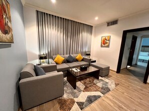 A modern living room with a sectional sofa, a coffee table, and a patterned rug. - Golden Tulip Al Khobar (Al Khobar)