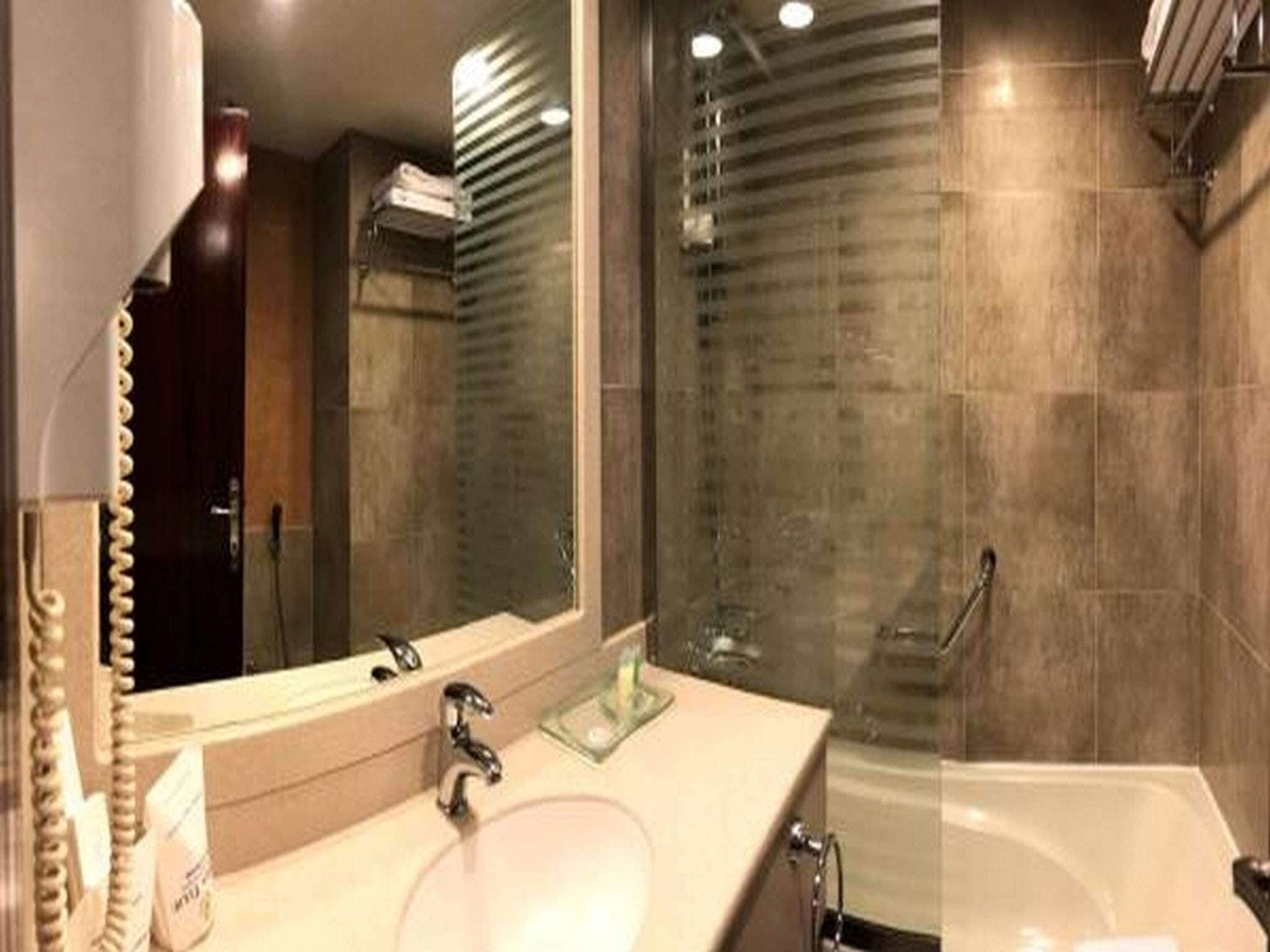 A modern bathroom with a large mirror, a sink, and a shower area.
