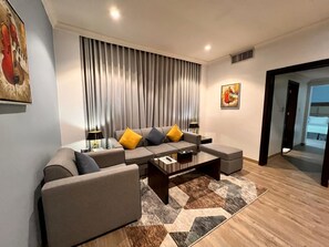 A modern living room with a sectional sofa, a coffee table, and a rug. - Golden Tulip Al Khobar (Al Khobar)
