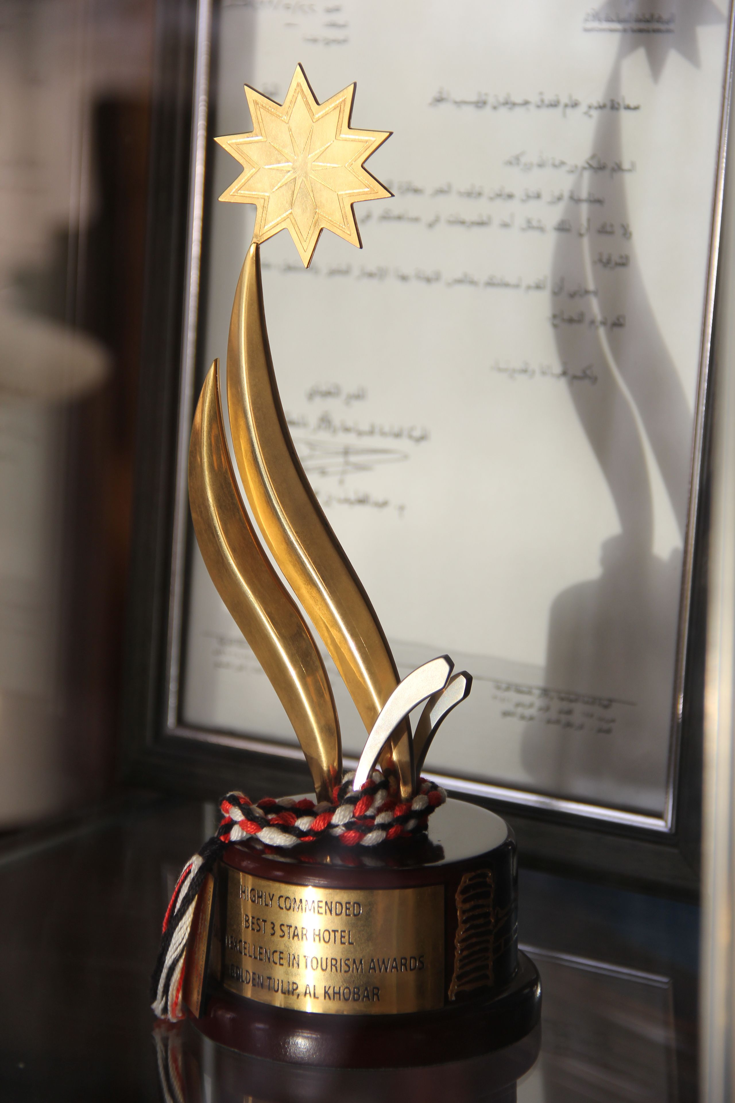 A trophy with a star on top, placed on a stand with a plaque that reads "Highly Commended Best 3 Star Hotel Excellence in Tourism Awards".