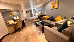 A modern hotel room with a sofa set, a dining area, and a bed. - Golden Tulip Al Khobar (Al Khobar)