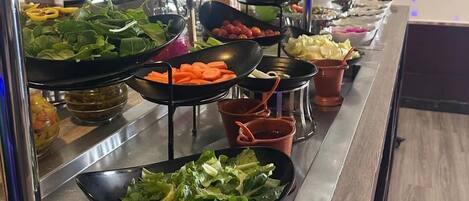 A buffet with various food items including salads, vegetables, and fruits.