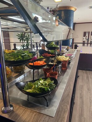 Ein reichhaltiges Buffet mit verschiedenen Speisen, darunter Salate, Gemüse und Obst.