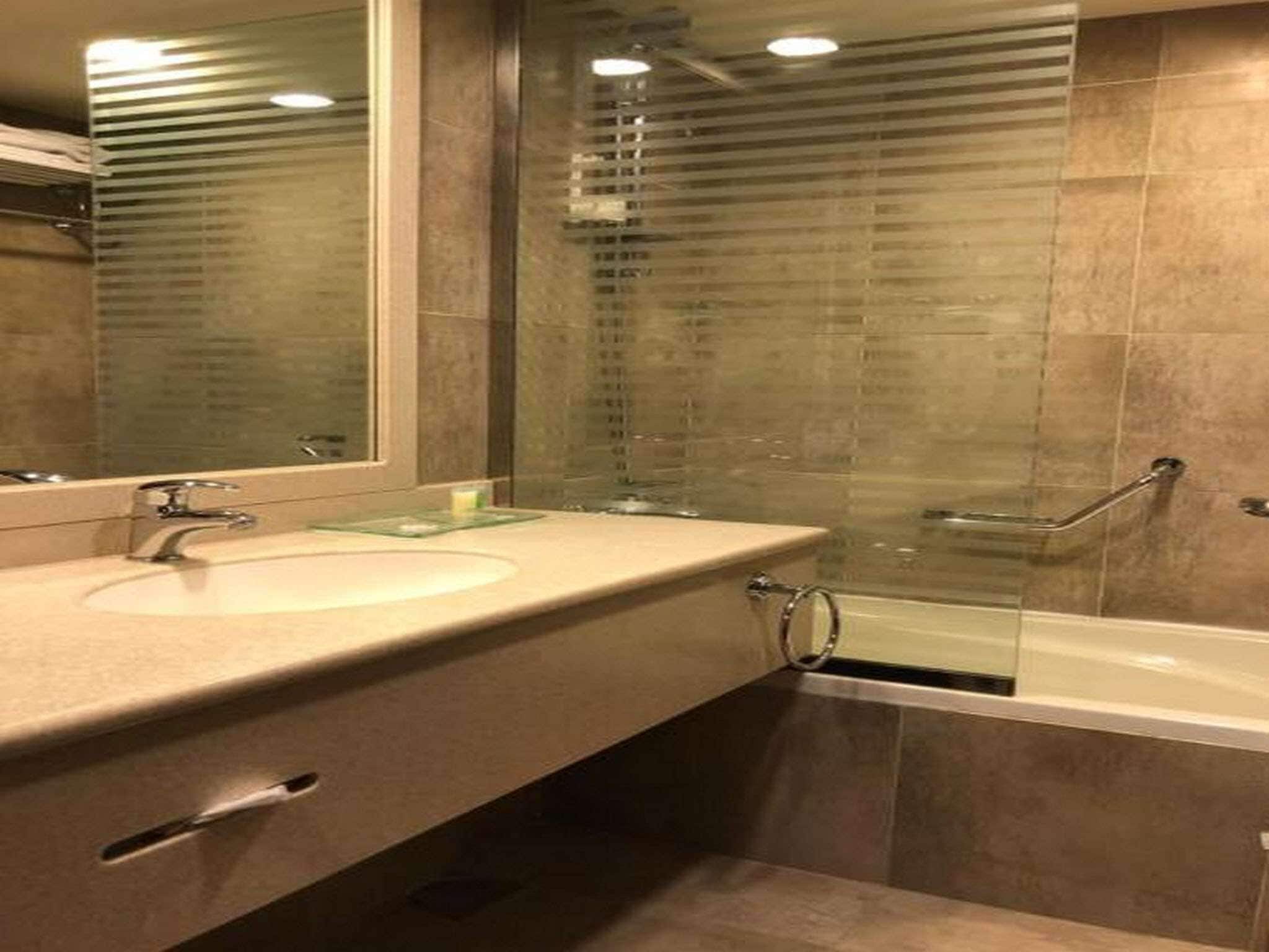 Un baño con lavamanos, espejo y ducha.