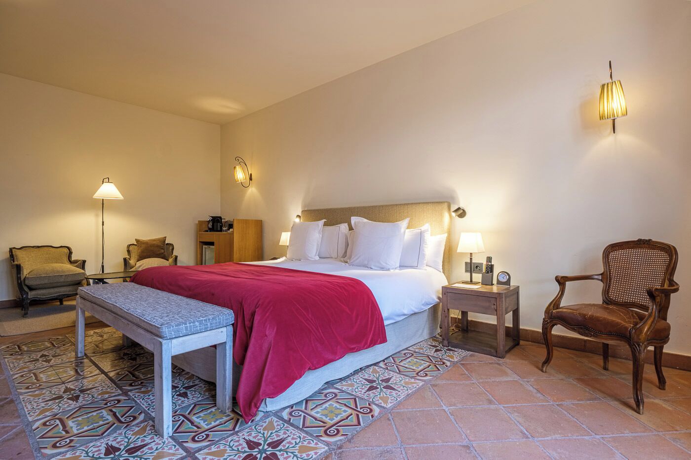 Una habitación de hotel con una cama grande, una mesita de noche, una silla, una lámpara y una mesilla.