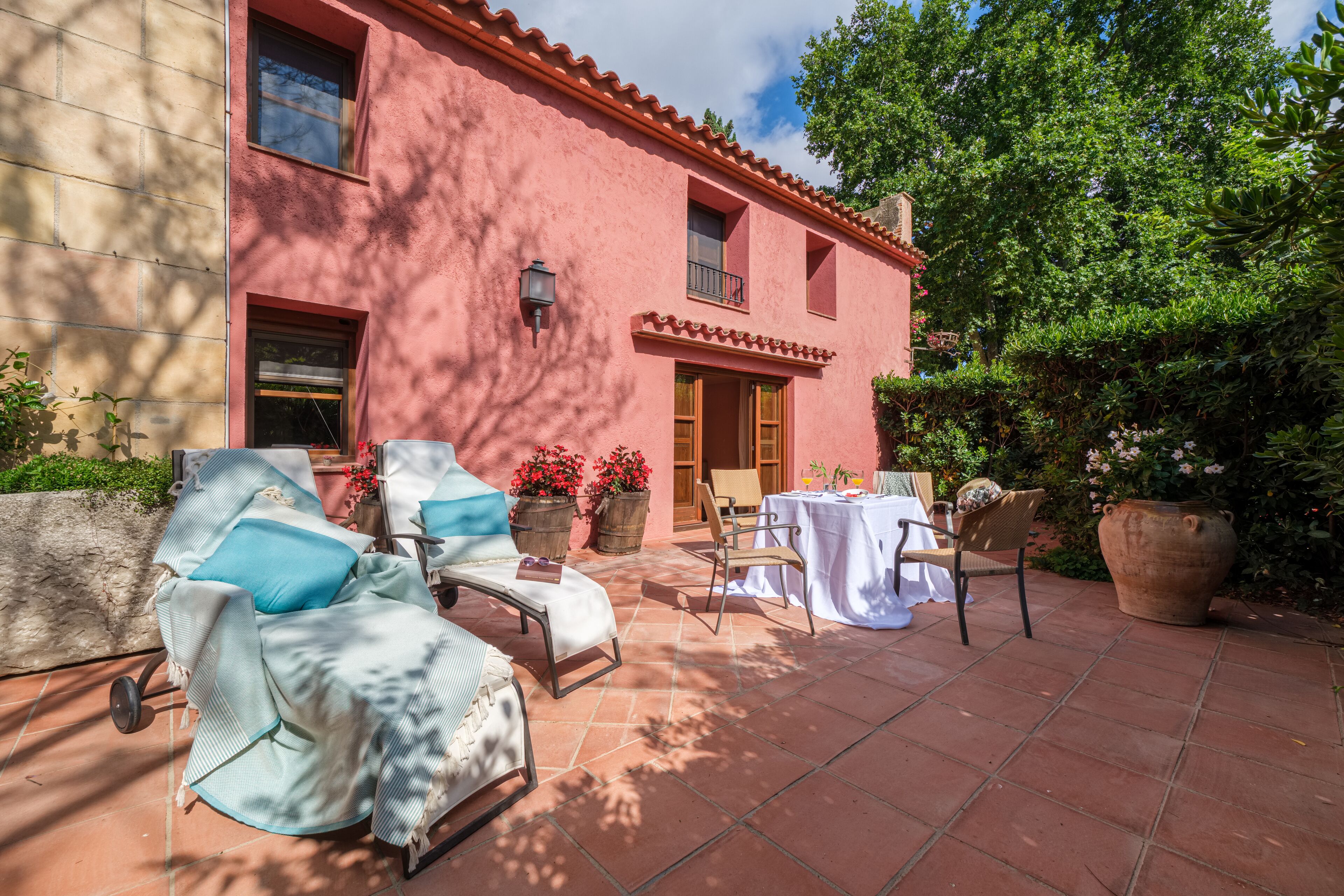 Eine Terrasse mit Gartenmöbeln, einem Tisch und Kübelpflanzen.