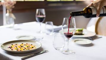 A table set for dining with a bottle of wine being poured into a glass.