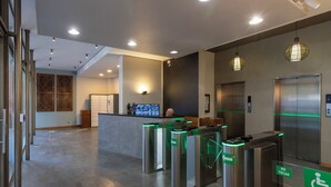 A modern lobby with a reception desk, a digital display, and a no-touch barrier.